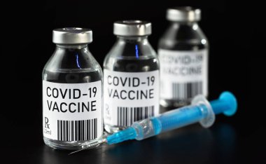 Coronavirus Covid-19 aşı konsepti - siyah masada üç cam şişe, yakın plan detayı (kendi tasarımı - sahte barkod) yanında mavi şırınga)