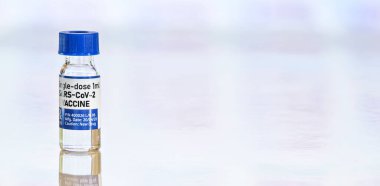 Coronavirus Covid-19 aşı konsepti - beyaz masada mavi başlıklı küçük cam şişe, metin sağ tarafı için geniş pankart alanı (çıkartma sahte verili kendi tasarımı, gerçek bir ürün değil)