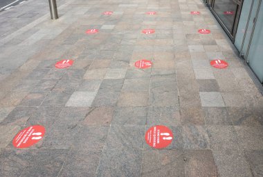 Londra, Birleşik Krallık - 14 Haziran 2020: Sokak zemininde kırmızı çıkartmalar insanları birbirine yakın olmayan kuyruklara sokmaya ve Coronavirus covid-19 salgını sırasında sosyal uzaklık çalışması yapmaya teşvik ediyor