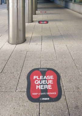Londra, Birleşik Krallık - 14 Haziran 2020: Sokak zemininde kırmızı çıkartmalar insanları birbirine yakın olmayan kuyruklara sokmaya ve Coronavirus covid-19 salgını sırasında sosyal uzaklık çalışması yapmaya teşvik ediyor