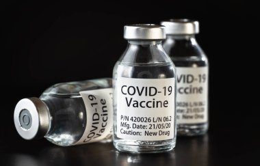 Coronavirus Covid-19 aşı konsepti - siyah masanın üzerinde üç cam şişe, yakın plan detay (kendi tasarımı - sahte veri, gerçek ürün değil)