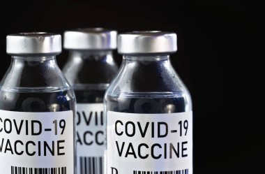 Coronavirus Covid-19 aşı konsepti - siyah masanın üzerinde üç cam şişe, yakın plan detay (kendi tasarımı - sahte barkod, gerçek ürün değil)