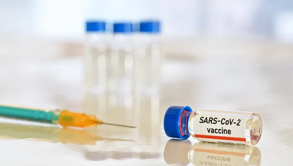 코로나 바이러스 Covid 백신의 개념작은 유리병 테이블에 파란색 오렌지색 주사기 — 스톡 사진