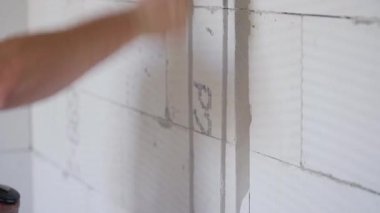 İnşaat işçisi elektrikli kablo takip kanallarını duvar keskisiyle genişletiyor. Detaylar elinde aleti tutuyor ve çekice vuruyor.