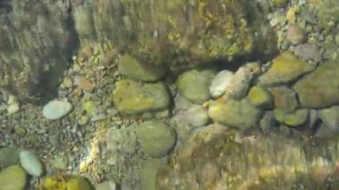 Güneş sığ denizde parlıyor. Yunanistan 'ın Korfu kentindeki Limni plajında küçük çakıl taşları. Deniz burada kristal kadar berrak.