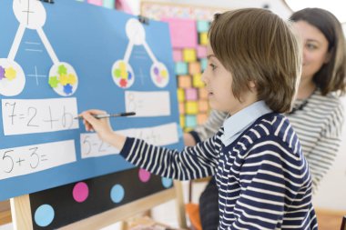 Sevimli çocuk anaokulu, eğitimci gözlem altında grafik matematik egzersizleri çözme