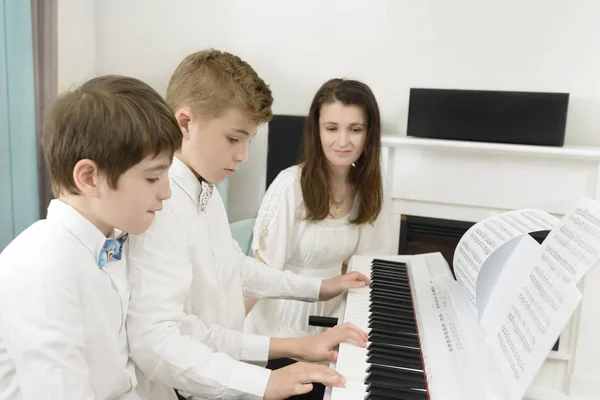 横に先生タンデムで遊ぶ電気ピアノ楽器で学ぶ子供たち — ストック写真
