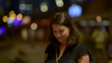 Güzel kadın, bir tablet bilgisayar kullanarak arka planda şehir ışıkları ile fotoğraf çekmek