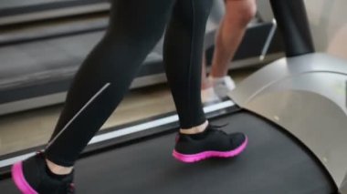 Spor salonu ve kişisel eğitmen tarafından Yardımlı, koşu bandı üzerinde çalışan güzel bir genç kadın