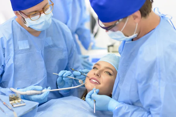 Médico dentista e sua equipe tratando um paciente — Fotografia de Stock