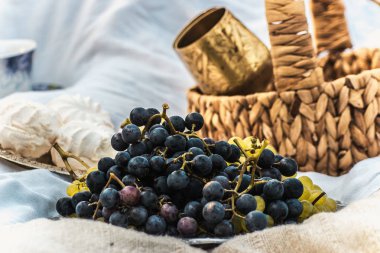 mavi üzüm, şekerleme, altın kadehler ve bir sepet piknik üzerinde