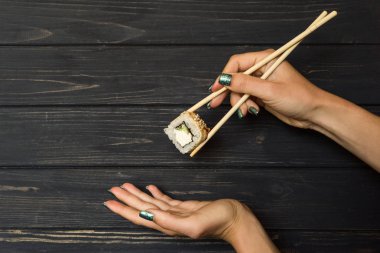 Suşi yemek çubukları siyah ahşap zemin ile tutan el