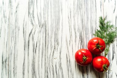 Domatesler ve yeşiller beyaz bir masada