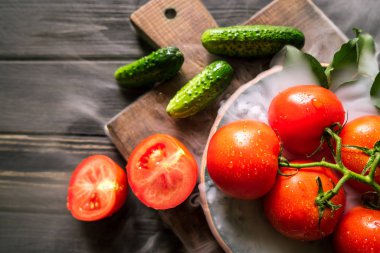 salatalık, domates ve duman siyah ahşap arka plan üzerinde kahverengi bir gemide