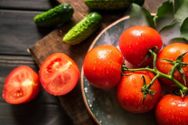 salatalık, domates ve duman siyah ahşap arka plan üzerinde kahverengi bir gemide