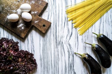 Patlıcan, makarna, yumurta ve marul üzerine beyaz ahşap zemin