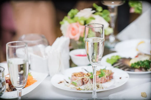 a glass of champagne and food at the festive table, wedding