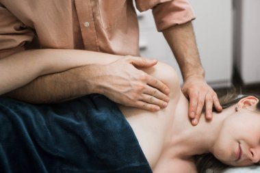 Profesyonel erkek masör kıza Tayland masajı yaptırıyor. Boyun, omuzlar, sırt, osteopati.