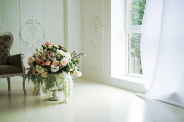 Birinci pencerenin yanında çiçekli vazo ve kanepe.