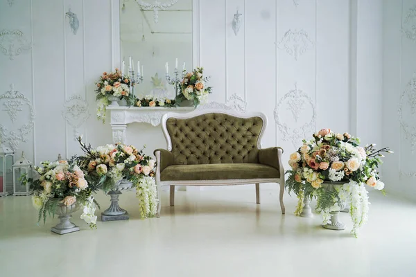 vintage sofa and vases with flowers stand near the mirror