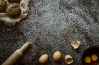 Ekmek, yumurta, merdane, mikser için malzemeler gri bir masada yatıyor.