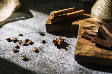Kahverengi tahta üzerinde kahve, tarçın, çikolata ve baharat yapımında kullanılan malzemeler.