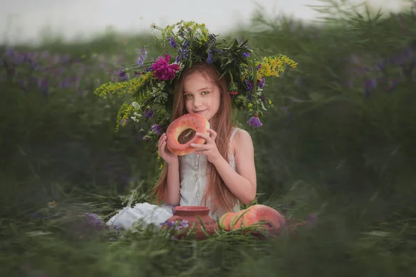 Menina em um campo com flores em suas mãos — Fotografia de Stock