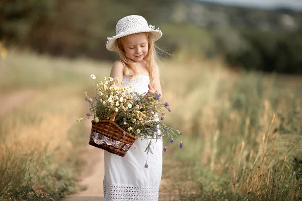 Κορίτσι σε ένα πεδίο με λουλούδια στα χέρια τους — Φωτογραφία Αρχείου