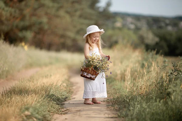 Fille dans un champ avec des fleurs dans leurs mains — Photo