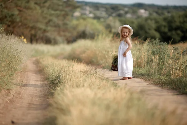 Menina em um campo com flores em suas mãos — Fotografia de Stock