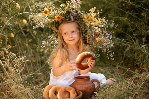 Menina em um campo com flores em suas mãos — Fotografia de Stock