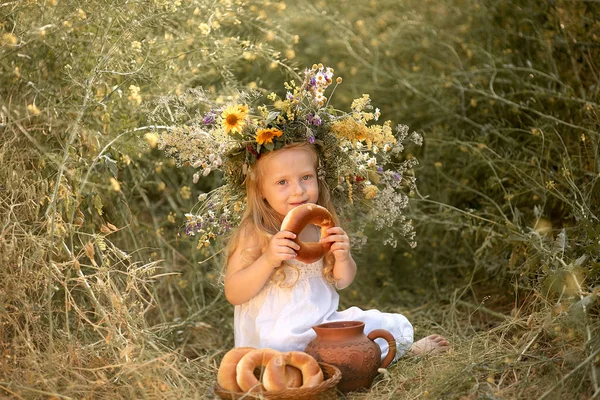 Menina em um campo com flores em suas mãos — Fotografia de Stock