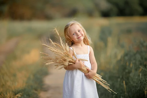 Fille dans un champ avec des fleurs dans leurs mains — Photo