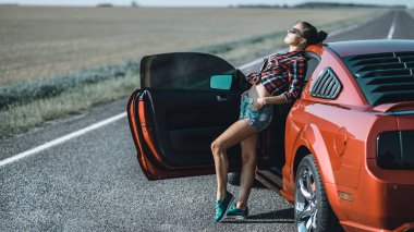 kısa şort giymiş güzel esmer kız ve kırmızı spor araba yakın güneş gözlüğü ile bir gömlek