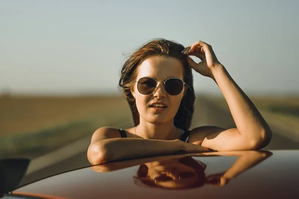 Beautiful Girl Bodysuit Long Hair Sunglasses Sits Hood Red Car — Stock Photo, Image