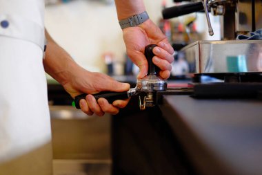 Barista kapuçino yapıyor, barmen kahve hazırlıyor.