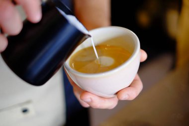 Barista kapuçino yapıyor, barmen kahve hazırlıyor.