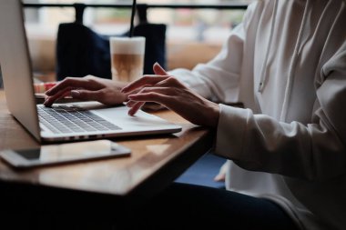 Kafede dizüstü bilgisayar kullanan bir iş kadını. Genç ve güzel bir kız bir kafede oturuyor ve bilgisayarla çalışıyor.