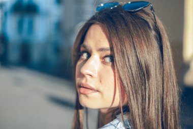 Sokakta yürüyen ve güneşli günlerin tadını çıkaran güzel bir kızın portresi.