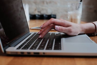 Laptop klavyesine manikür yazan, sosyal ağlarla iletişim kuran güzel bir kızın yakın plan görüntüsü.