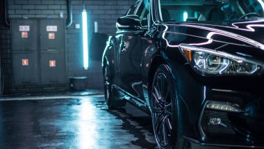 Modern lüks spor arabasının far ışığını kapat. Yıkama ve ağda üzerine yansıyan kırmızı boya. Duvarı tuğlalı süper arabanın ön manzarası. Araba temizliği ve boya koruma arkaplanı kavramı.