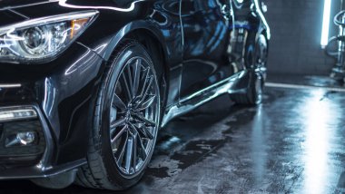 Modern lüks spor arabasının far ışığını kapat. Yıkama ve ağda üzerine yansıyan kırmızı boya. Duvarı tuğlalı süper arabanın ön manzarası. Araba temizliği ve boya koruma arkaplanı kavramı.