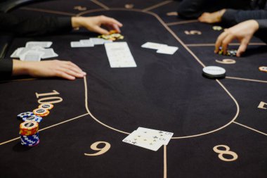 Krupiye ya da krupiye kumarhanedeki poker kartlarını masanın arka planında karıştırıyor. Poker konsepti, oyun işi. Para için oynamak, büyük bir galibiyet, büyük ikramiye, kumar, zengin olma arzusu..