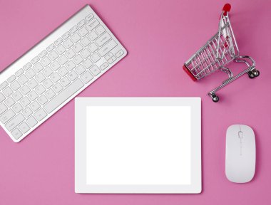 Kadınsı işyeri kavramı. Alışveriş sepeti ve tablet. Online alışveriş kavramı. Üstten görünüm parlak pembe arka plan öğeleri. bir tablet üzerinde pembe bir tablo. Düz yatıyordu. Uzay kopyalayın. Tablet etli, anahtar yönetim kurulu ile pembe tablo üzerinde beyaz ve fare. 