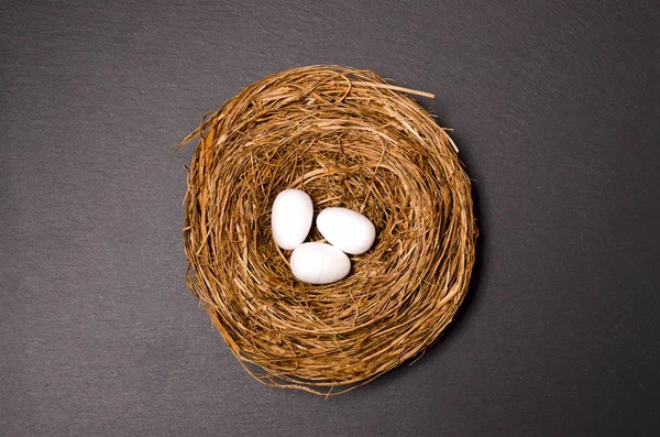 Easter nest on black background. white Easter eggs in nest on pastel color background with space. Black background. Minimalism.