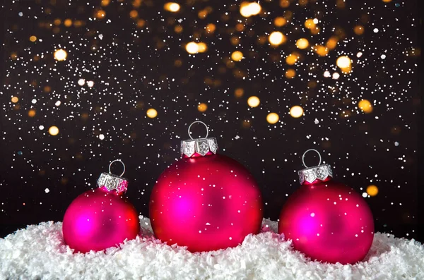 黒の背景にぼやけた魔法の光と雪のクリスマス紫色のボール. — ストック写真