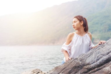 Kadınlar touch rock ve dağ ve deniz wave.she ile arka plan beyaz elbise ve uzun saçları giymek.