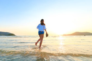 seyahat kadınlar tutun şapka ve plaj su üzerinde çalışan.