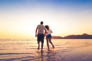 Sahilde günbatımı arasında çift çalışan ve el tutun.