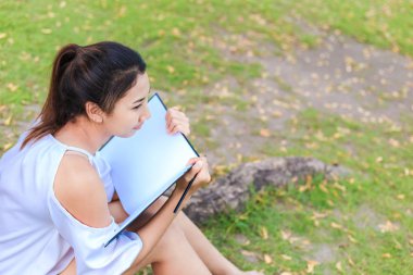 Büyük ağacın yanında oturan ve parkta çizim kadın.